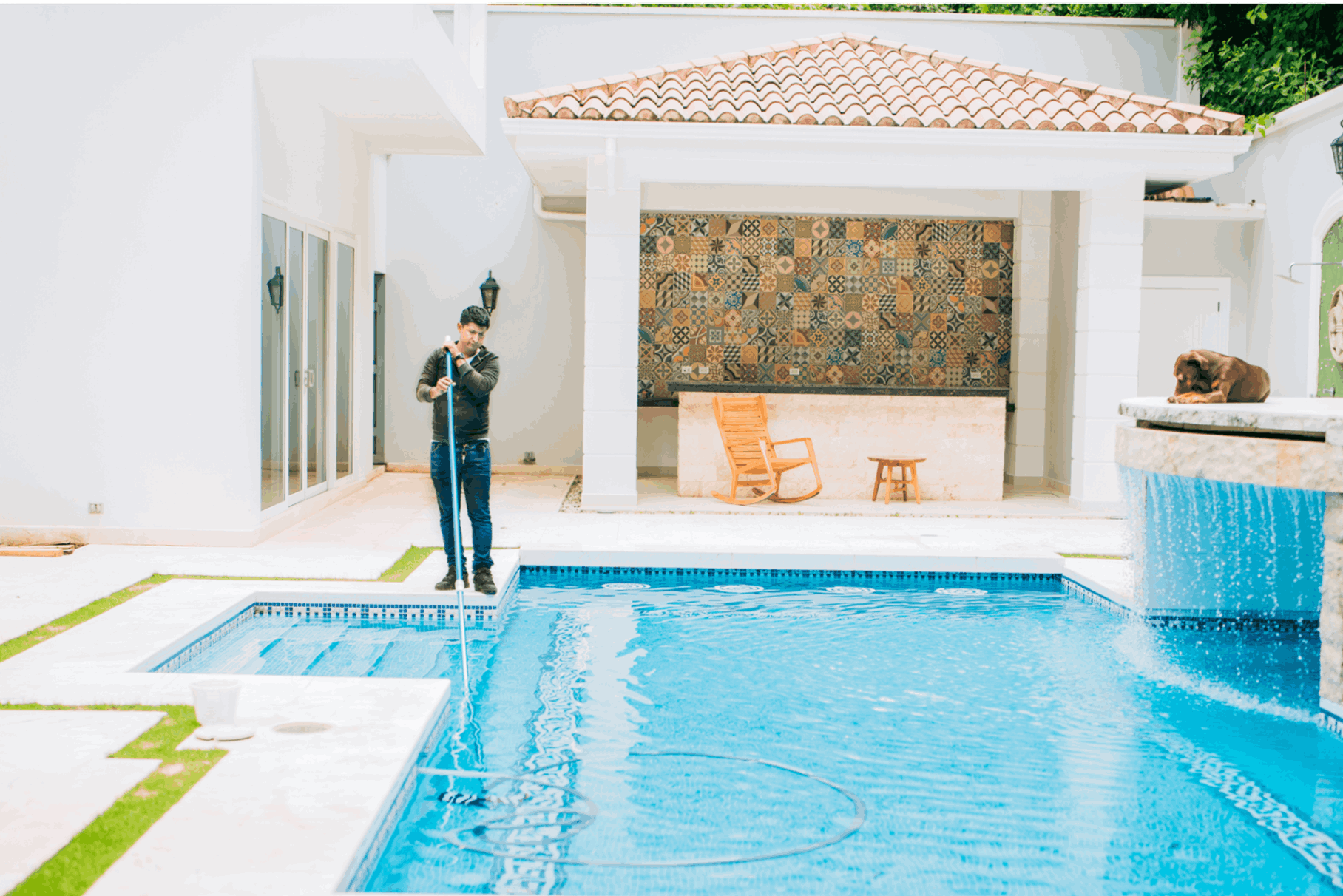 Person cleaning a luxurious outdoor swimming pool.