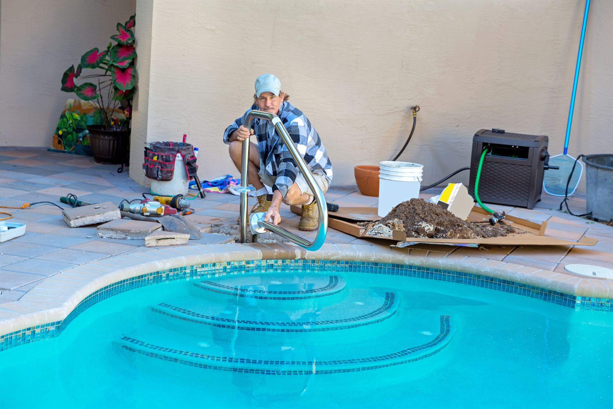 Worker repairing poolside equipment and pipes.